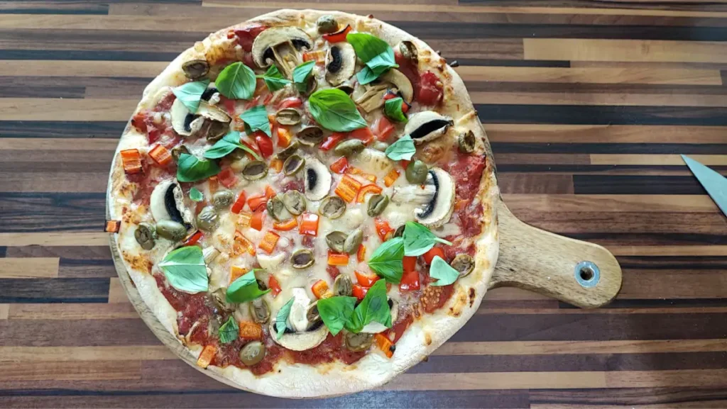 Selbstgemachte vegane Pizza mit einfacher Tomatensauce, Zwiebeln und Kräutern auf knusprigem Teig.