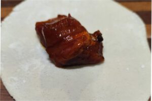 Placing a spoonful of filling onto the center of each round mandu wrapper before folding 02