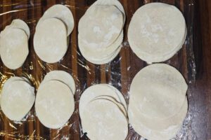 Cutting round mandu wrappers from the rolled-out dough using a cutter or glass