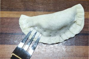 Folding the mandu wrapper into a half-moon shape to enclose the filling