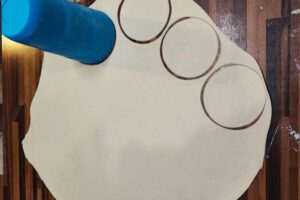 Thin mandu dough being rolled out and cut into round wrappers for Korean dumplings