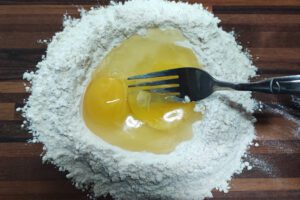 Eggs being whisked into flour using a fork
