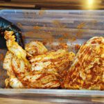 Gleichmäßig mit Paste bestrichene Kohlviertel für das historische Kimchi Rezept schichten