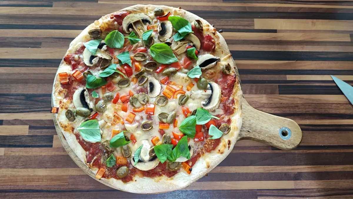 Selbstgemachte vegane Pizza mit einfacher Tomatensauce, Zwiebeln und Kräutern auf knusprigem Teig.